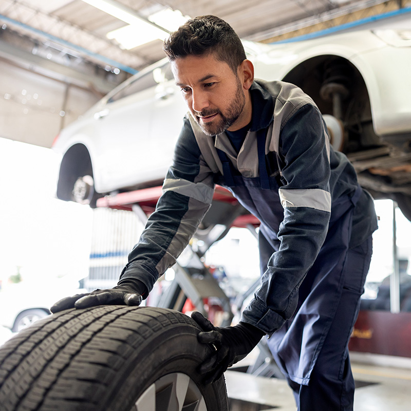 Happy mechanic changing a flat tire on a car