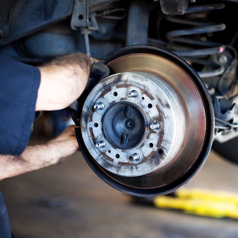 Auto mechanic working on brakes in a car repair shop