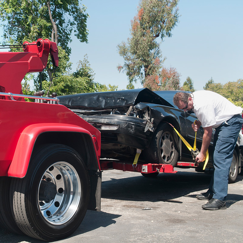Tow Truck Driver Hauling a Wrecked Car